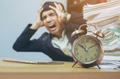 Business: Stressed man with pile of paperwork works against the clock