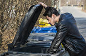 man in leather jacket rummages through bin