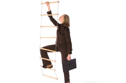 Woman attempts to climb rope ladder in business suit