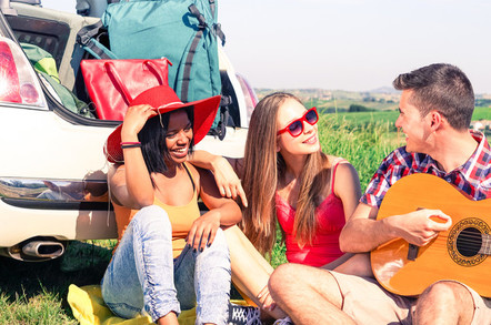 youngsters going to a music festival - man plays guitar, boot packed with luggage
