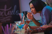 Woman pulls face while tasting dubious cocktail. 