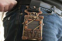 Belt with antique looking cellphone strapped to it in a brass pouch