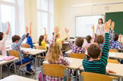 kids in classroom with raised hands