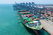 Container ship docked at port with crystal blue waters. 