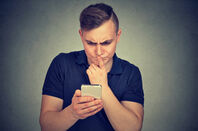 man peers at mobile/cell with bewildered expression