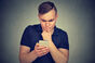 man peers at mobile/cell with bewildered expression