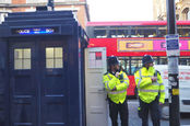 Met police coppers in high vis yellow vests in front of a police box