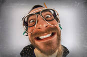 Bearded man with crazed expression wearing multiple pairs of glasses