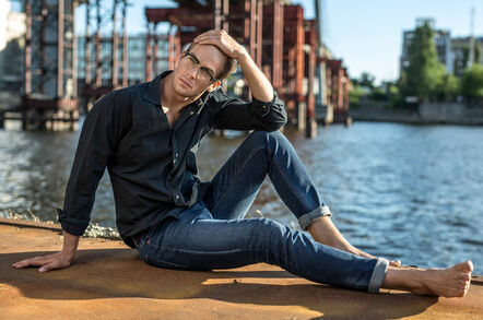 Tall, slim male model poses by canal
