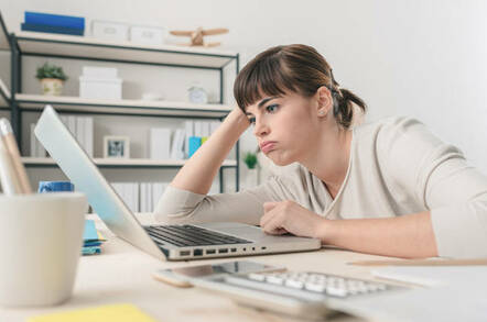 Tired disappointed woman working at office desk with a laptop