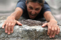 Climber hanging off a cliff edge