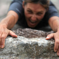 Climber hanging off a cliff edge