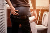 A man holds in his poo while looking at the toilet