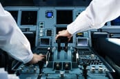 Two pilots operating on the controls of a commercial jet aircraft