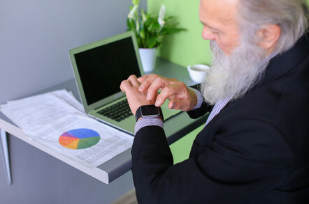 Older bearded man inputs data from a printed chart into a computer