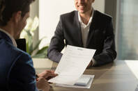 Employer looks at smiling candidate&#39;s CV