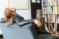 An audiophile leaning back on a couch listening to music