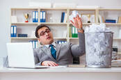 Man in office flippantly throws balls of paper in bin