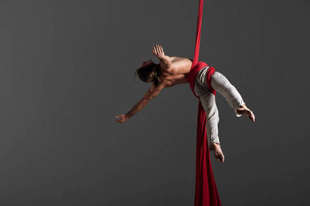 acrobatic yoga performed by man sliding down fabric