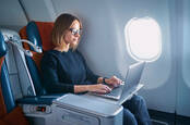 young business woman working on laptop computer while sitting in airplane