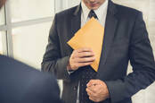 Man in suit sticks brown paper envelope in jacket