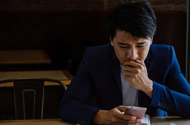 Man looks at cellphone mobile phone in despair