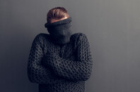 Young man covers face with jumper