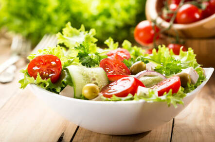 bowl of salad with vegetables and greens on wooden table