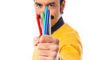 Man holds out fistful of  crayons 