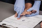 man gets fingerprinted by gloved person