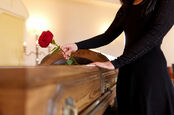 Woman with red roses and coffin at funeral in church