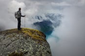 Man with hiking equipment standing on rock's edge