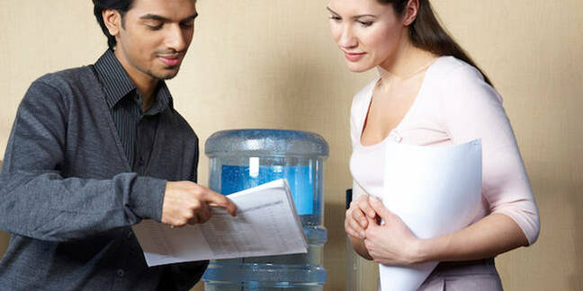 Two people standing talking by a water cooler