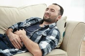 Man suffering from stomach ache while lying on sofa