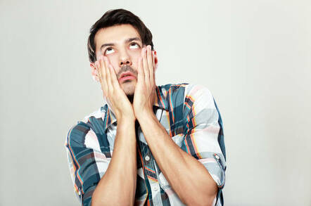 A man holding his face in his hands and rolling his eyes