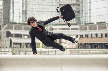 Business man with suitcase jumping over urban obstacles