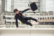 Business man with suitcase jumping over urban obstacles