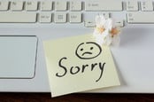 Handwritten note on keyboard saying sorry with sad face