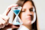 Someone holding an hourglass of blue sand