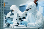 techies work in scrubs / clean room microscopes on components 