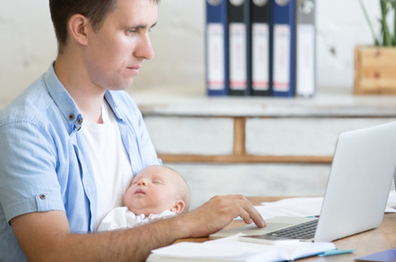 Dad with sleeping baby on laptop. Pic Shutterstock