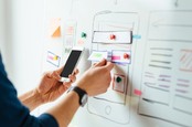 Person holding smartphone during whiteboard web design session