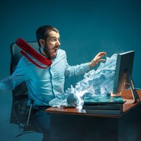 Man at desk overwhelmed by flood of messages