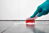 A male hand scrubs a floor