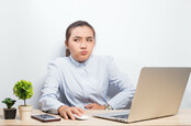 Woman looks sceptical at laptop