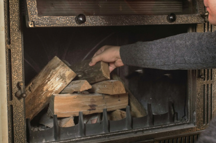 Man stacks pre-cut wood in a fireplace