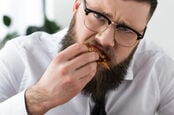 man in tie eats slice of pizza, looks sad while doing so 