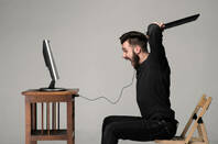 Angry man wields keyboard at a computer