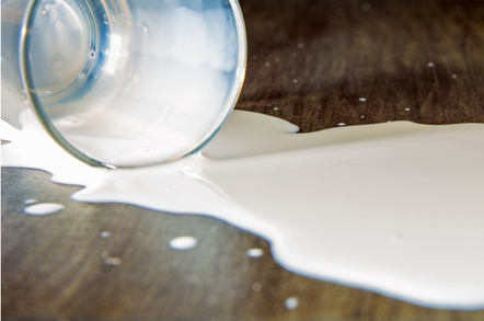 Tilted glass with milk lying on a table