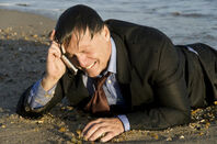 crying business man washed up on beach talks into phone